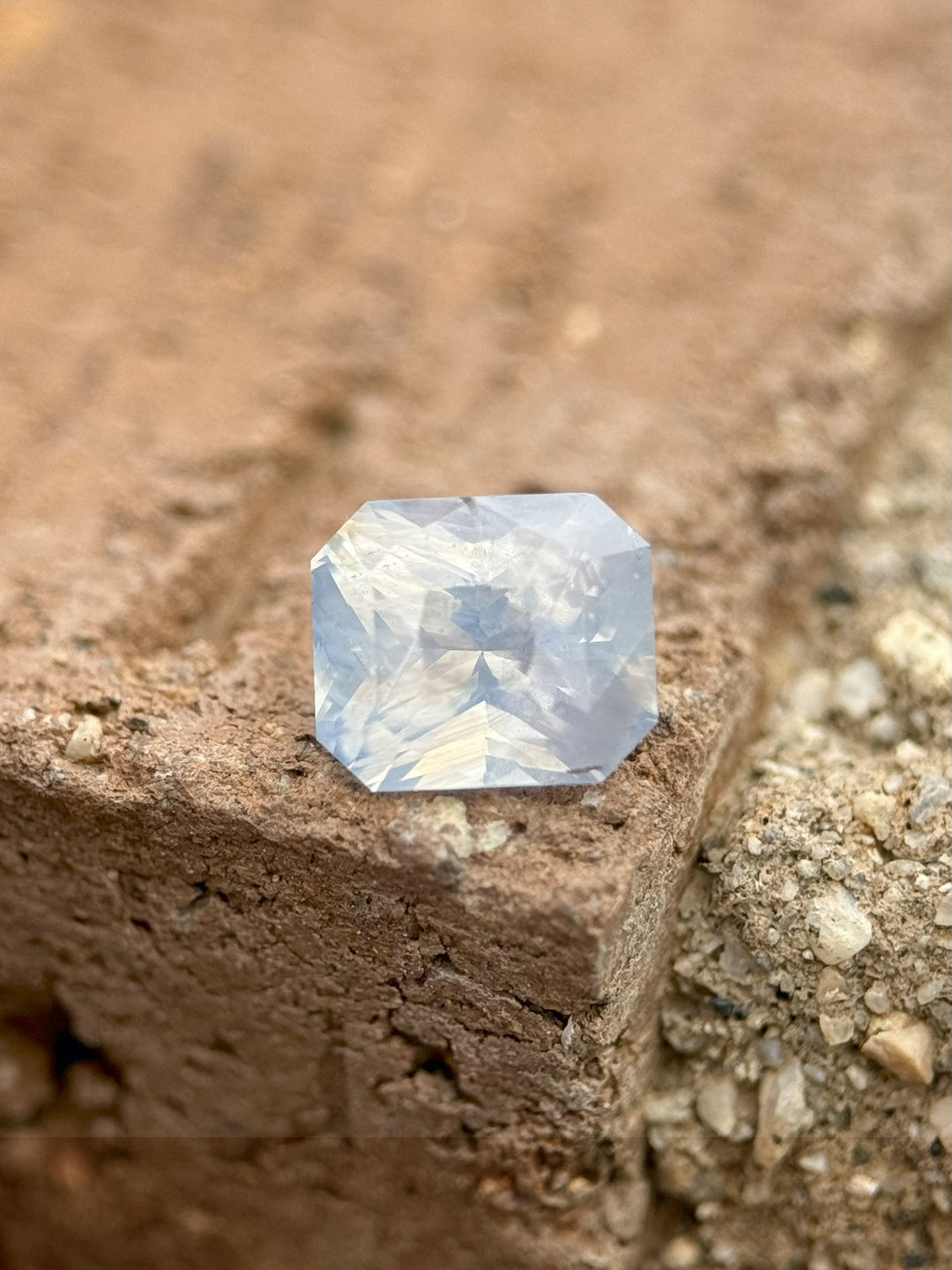 Unheated 1.58 carat sapphire on textured stone surface, revealing its unique opalescent shimmer and radiant facets