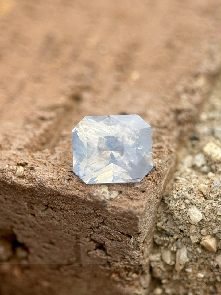 Unheated 1.58 carat sapphire on textured stone surface, revealing its unique opalescent shimmer and radiant facets