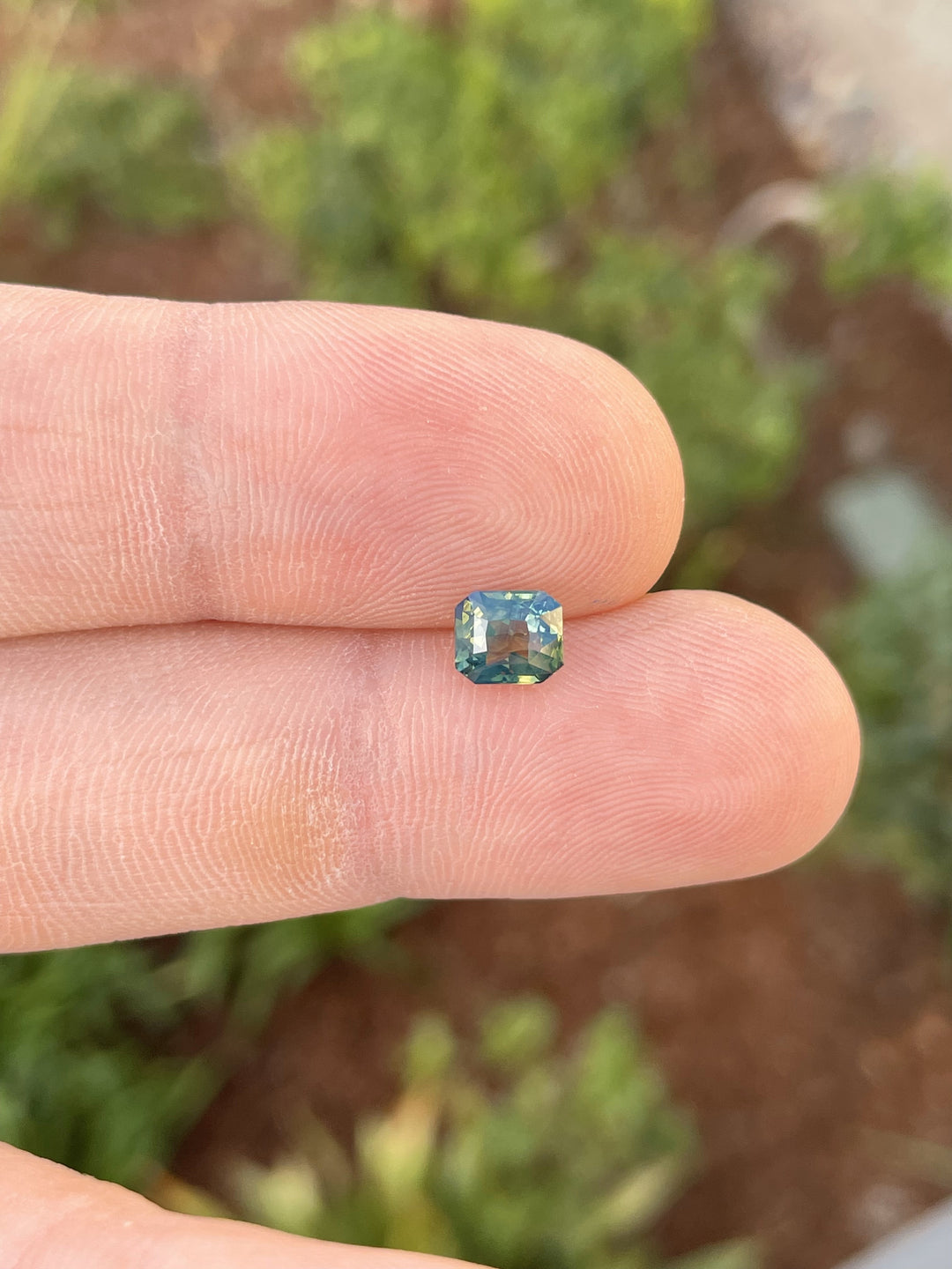 A 1.42-carat sapphire in a radiant cut featuring a mesmerizing mix of opalescent yellow, teal, and green tones. The gemstone is untreated and ethically sourced from Madagascar.