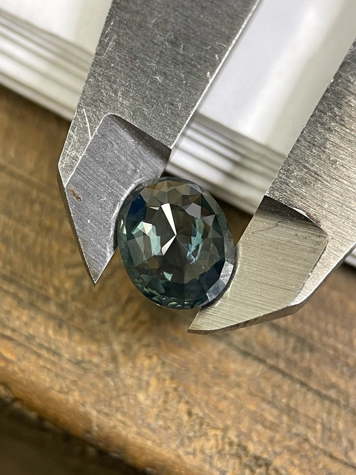A 1.72-carat sapphire showcasing green, blue, and teal tones with a mix cut oval shape. This untreated gemstone is ethically sourced from Madagascar, offering exceptional brilliance.