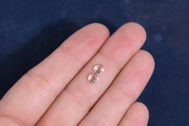 Two matching fancy brown Mughal cut diamonds displayed on fingertips for scale, totaling 1.45 carats with VVS1 clarity, antique hand-cut style, and natural untreated South African origin.