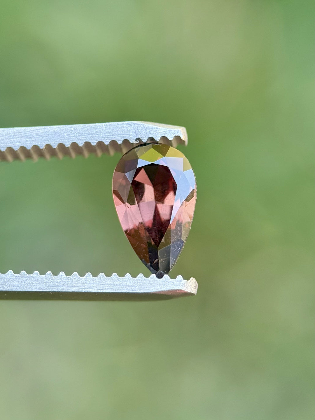 Side profile view of a modified brilliant pear cut sapphire with red-purple color shift, weighing 1.39 carats