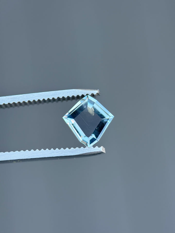 Side view of 1.52ct color change sapphire from Montana, suspended in tweezers to showcase clarity and sharp faceting.