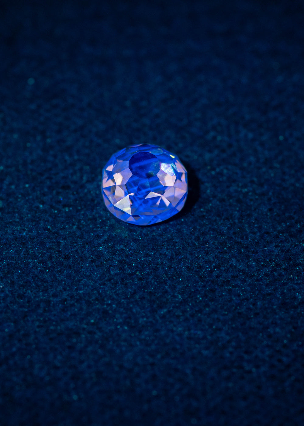 0.83ct Mughal Cut Diamond under strong blue fluorescence, glowing vibrant blue against a dark textured surface, Fancy Light Brown C2 VVS1 untreated South African diamond.