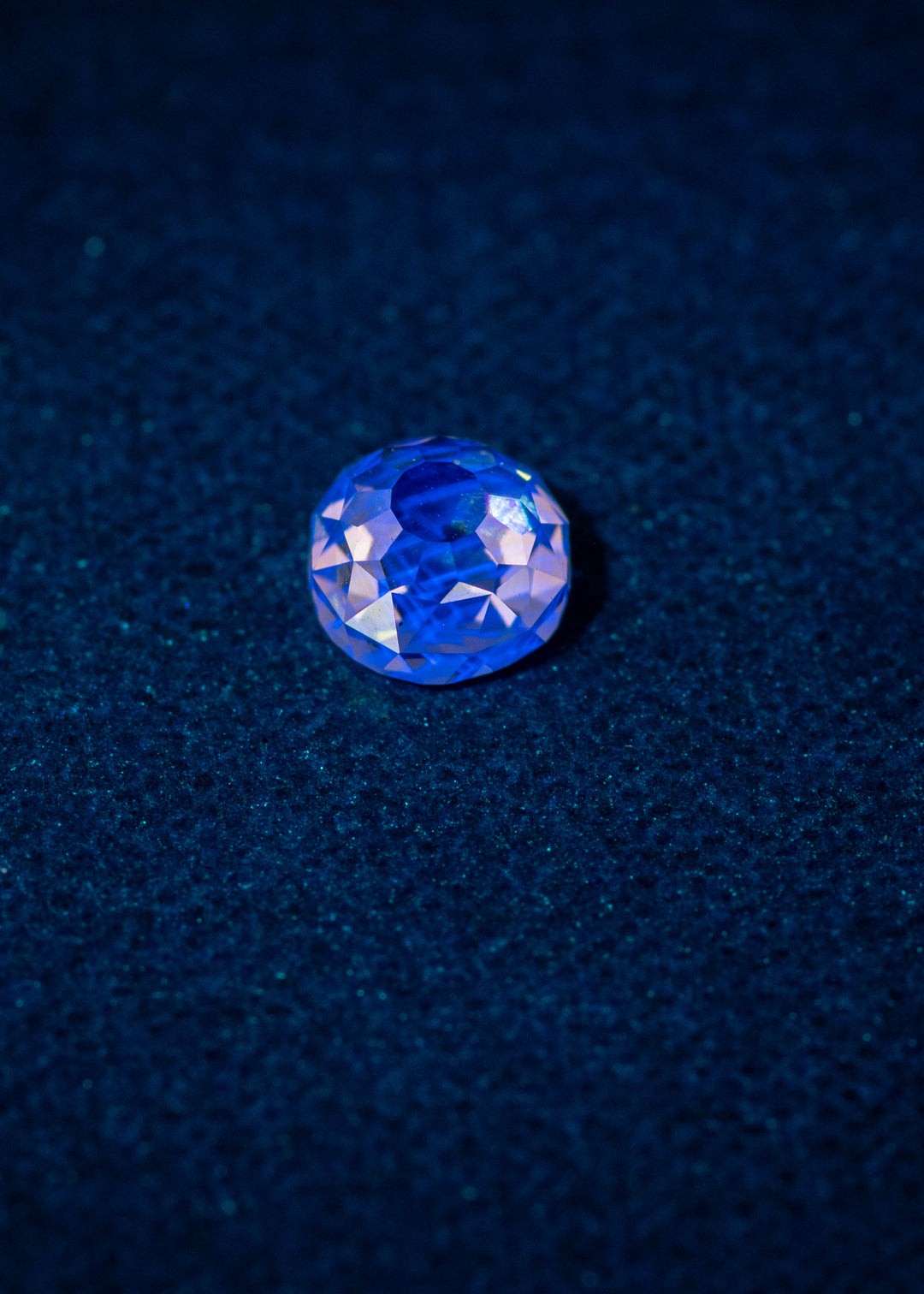 0.83ct Mughal Cut Diamond under strong blue fluorescence, glowing vibrant blue against a dark textured surface, Fancy Light Brown C2 VVS1 untreated South African diamond.