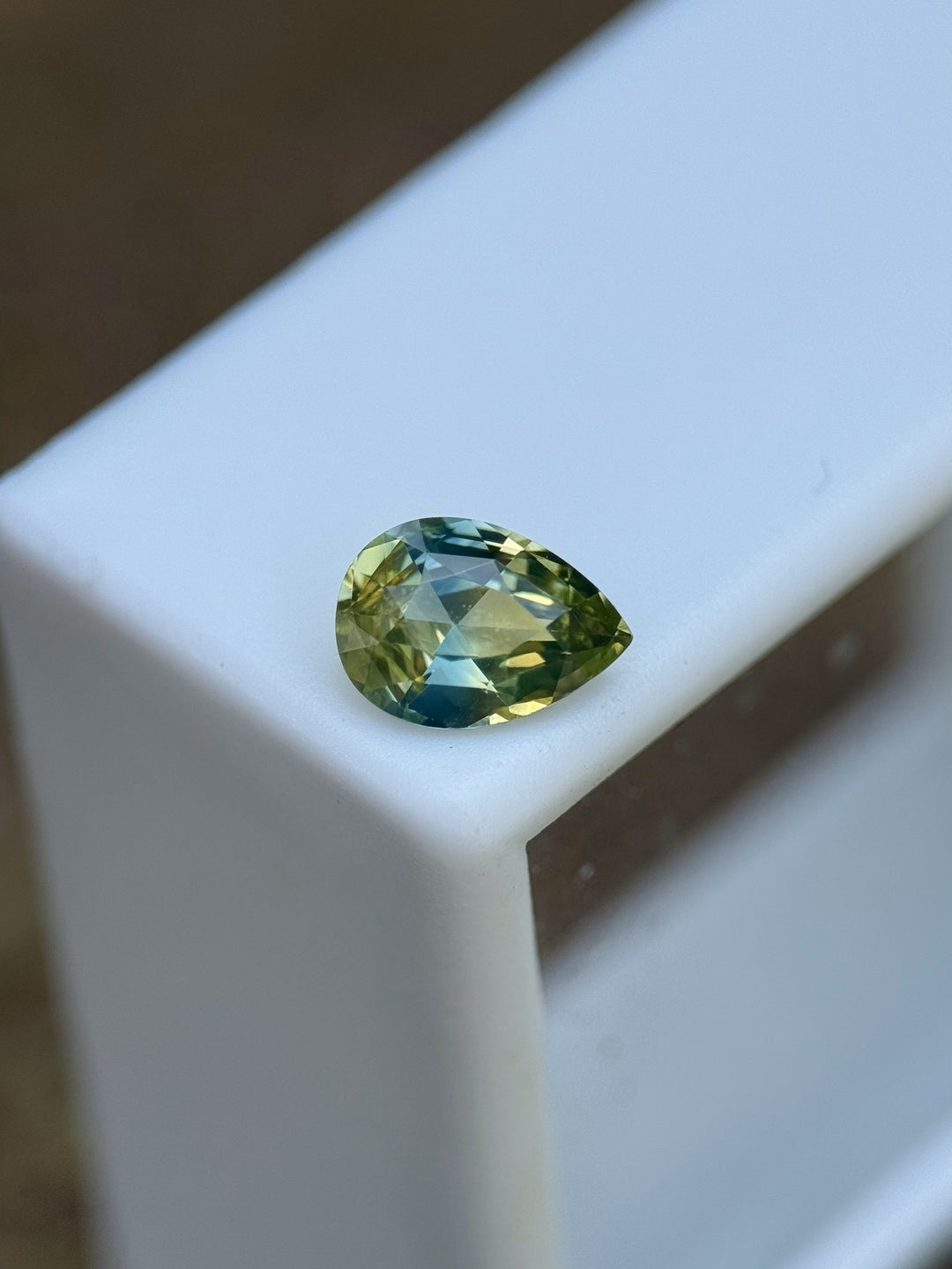 Natural untreated Madagascar sapphire with a pear brilliant cut and mixed colors, on a gem tray.