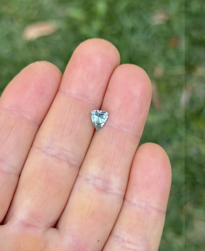 1.08 carat shield-shaped sapphire displayed on fingers in daylight, showcasing blue and teal brilliance from Chimwadzulu Hill.