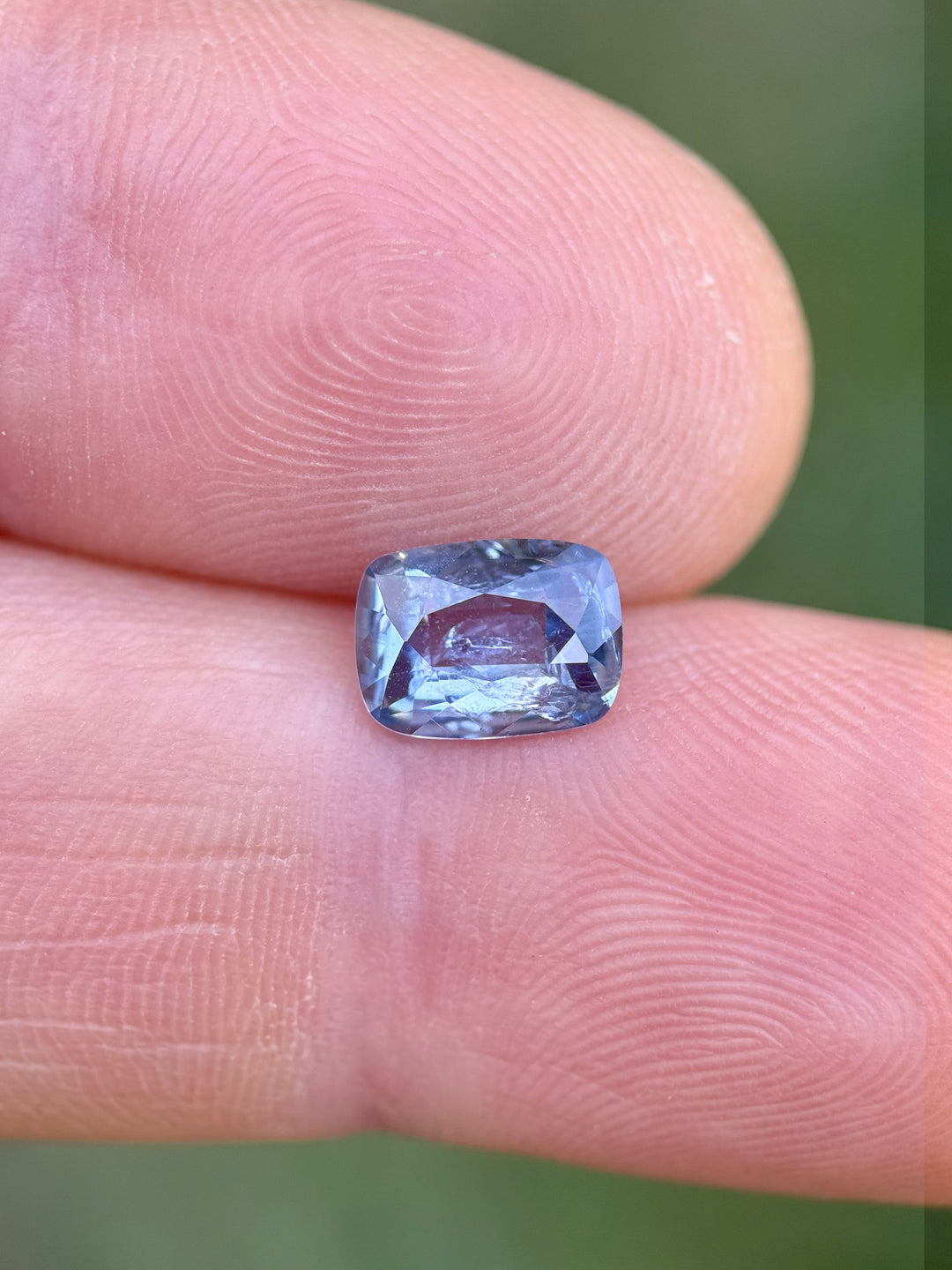 Elongated cushion cut periwinkle blue sapphire weighing 1.33 carats shown on finger for scale, unheated Ceylon origin