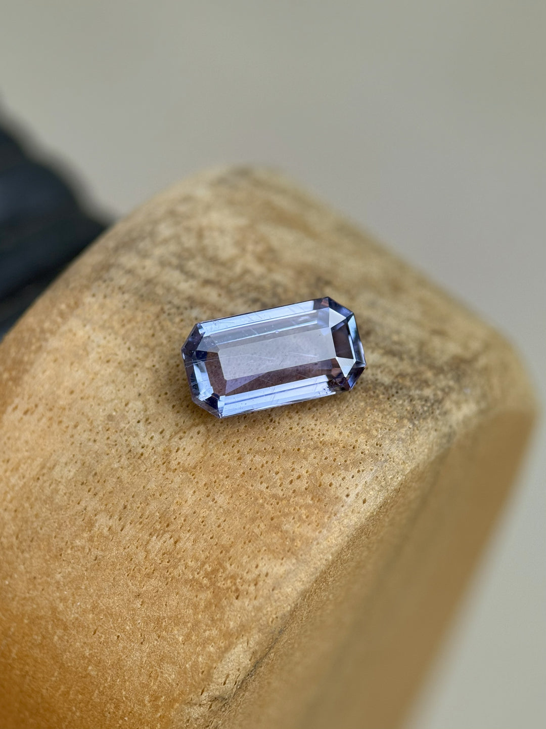 Unheated 1.41 carat Umba River sapphire with violet and blue hues in modified emerald cut resting on wooden surface