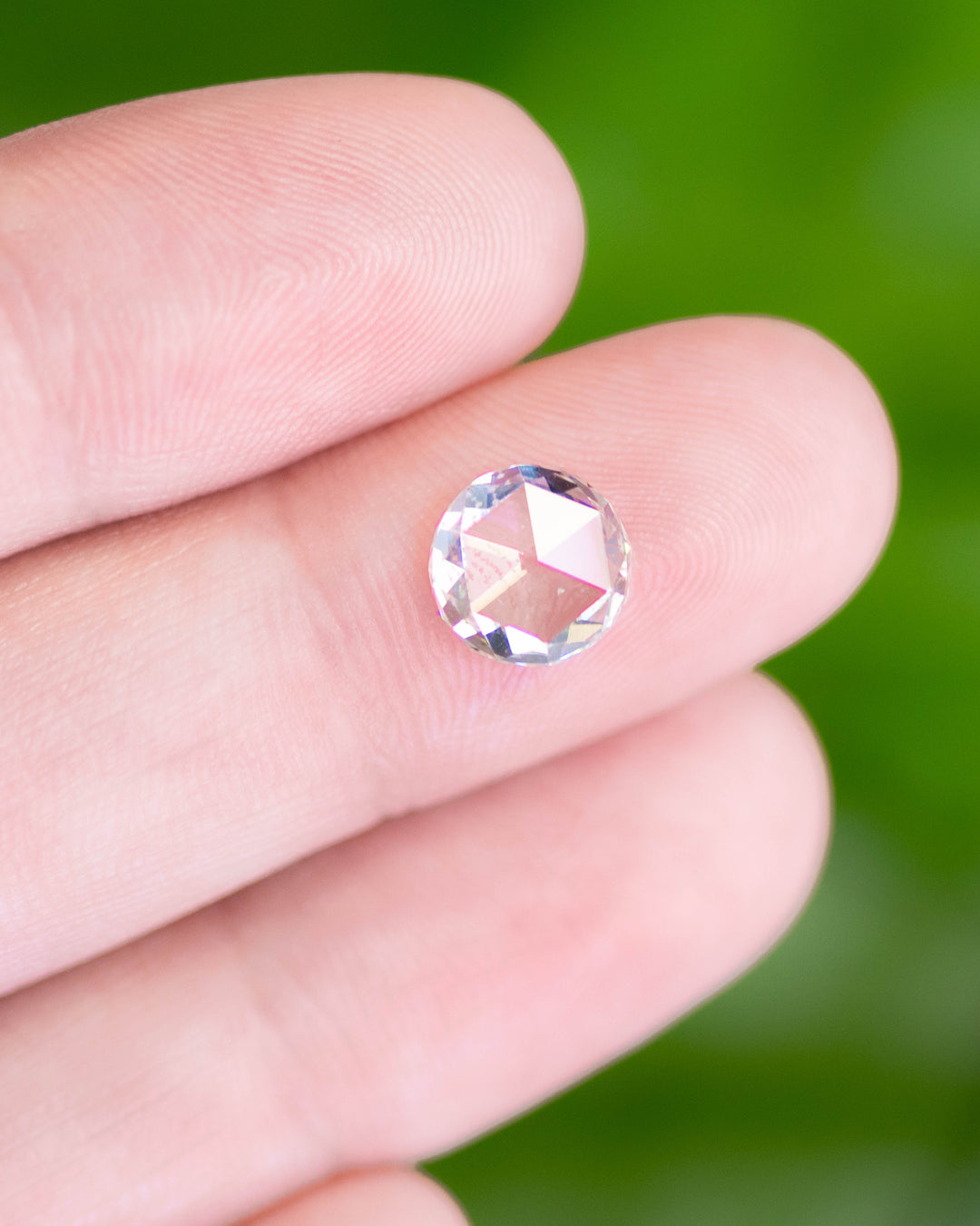 1.62 carat light green rose cut diamond from South Africa displayed on a fingertip. The GIA certified, laser-drilled natural diamond exhibits open faceting and soft brilliance with subtle green tones.