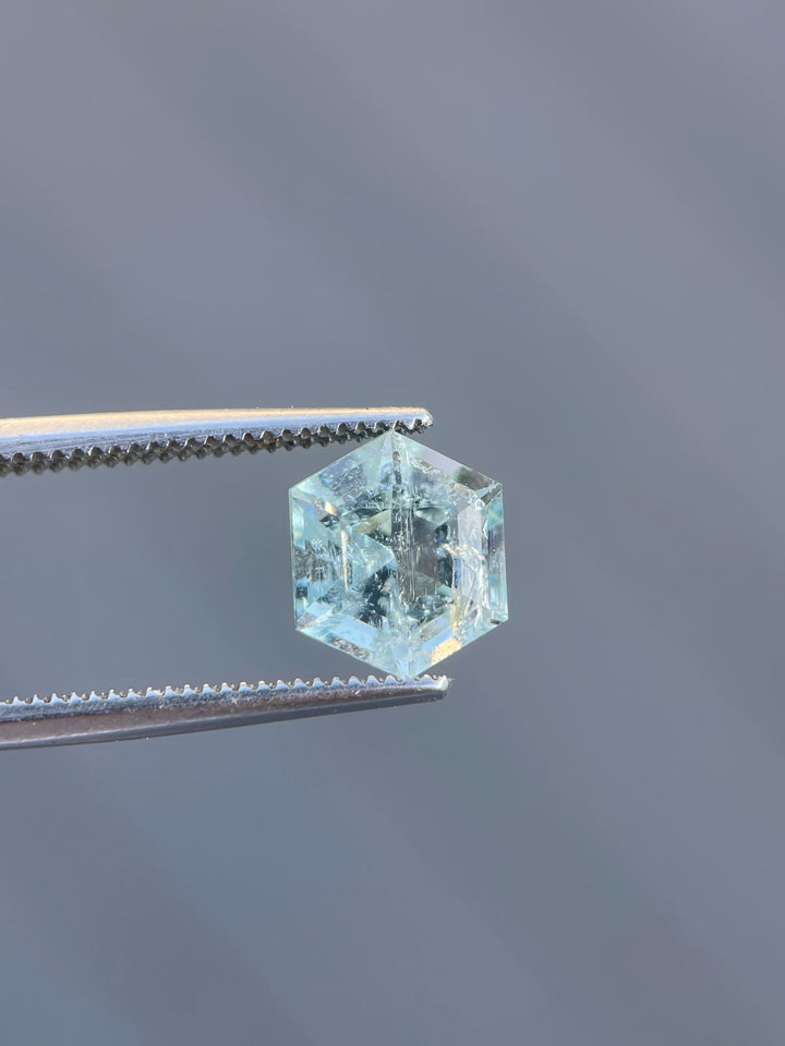 A stunning 2.20ct Green Beryl held in gem tweezers, displaying its precise step-cut facets against a neutral background.