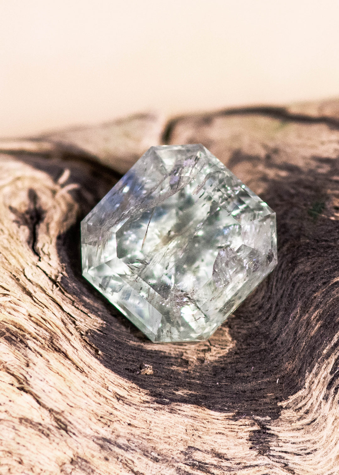 2.25 carat untreated Montana sapphire in a seafoam and teal Asscher cut resting on natural weathered wood, showing crisp step facets, internal crystal texture, and natural inclusions in daylight macro photography.