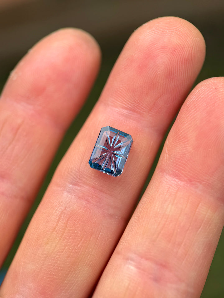 Natural 2.99ct Tanzanite in a violet-teal-blue octagonal concave portrait cut resting on fingertips, demonstrating size, brilliance, and Merelani Hills origin.