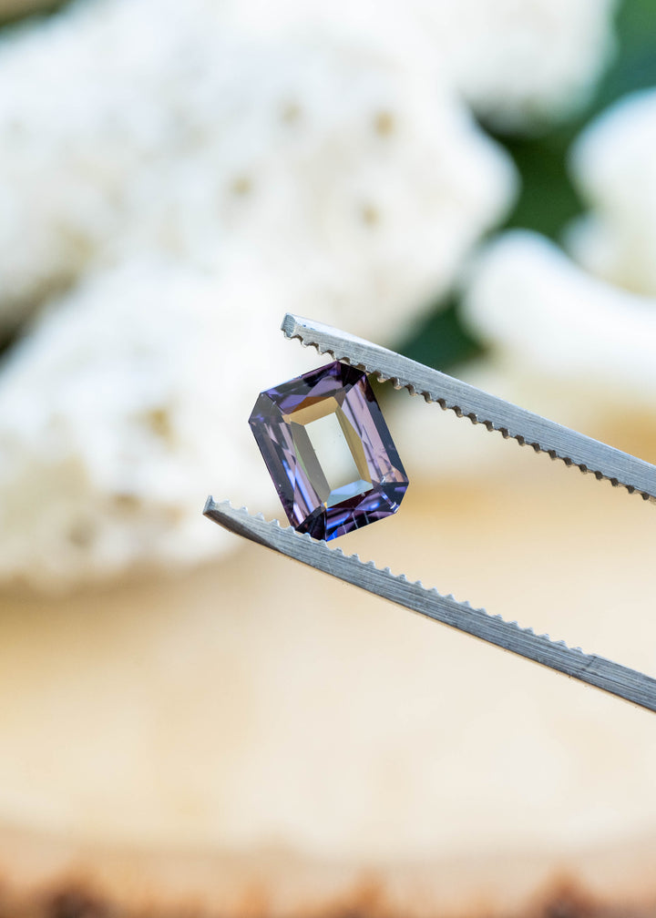 Close-up of a natural 1.19 carat untreated Merelani Hills tanzanite in tweezers showcasing its custom radiant portrait cut and pleochroic green and purple color.