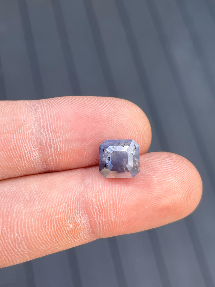 A unique 5.92-carat heated sapphire in emerald cut, displayed on a fingertip to showcase its size and clarity.