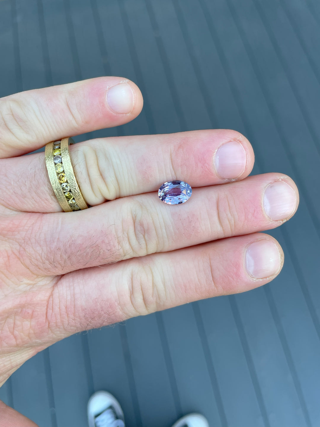 A mix brilliant oval-cut purple sapphire from Sri Lanka, weighing 2.56 carats, displayed against natural surroundings, untreated and vibrant.