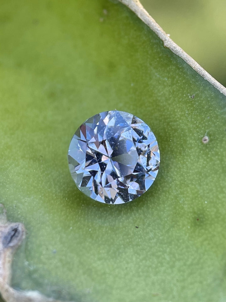 Close-up of a 2.52-carat lilac pink sapphire on a green leaf, showcasing fine faceting and soft pastel hues in an antique-inspired brilliant cut.