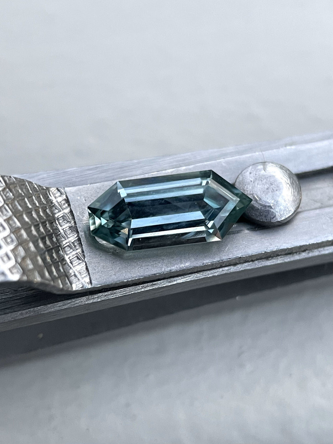Hand-cut 1.05 carat sapphire from Montana, expertly crafted in a bullet-shaped septagon cut, sparkling with blue and teal hues.