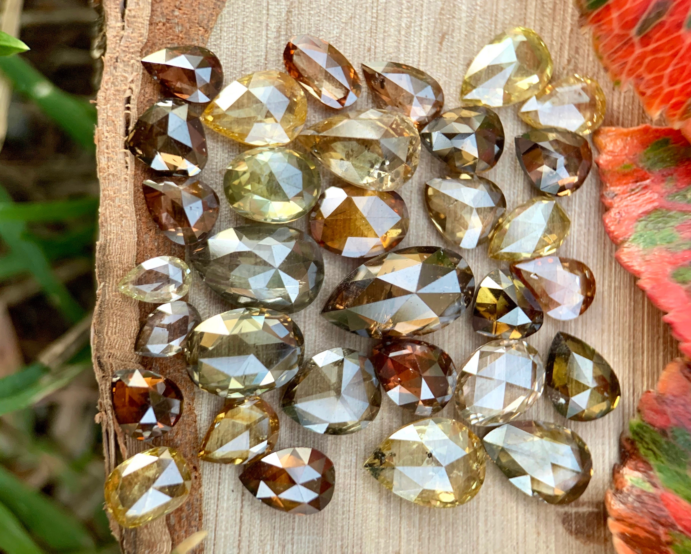 Natural rose cut diamonds in champagne, cognac, yellow, and gray tones arranged on wood for custom jewelry sourcing.