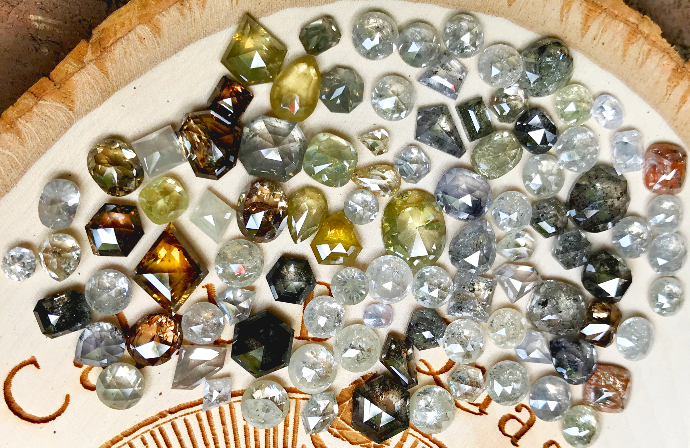 Natural rose cut diamonds in white, gray, champagne, yellow, and cognac tones arranged on wood for custom jewelry sourcing.