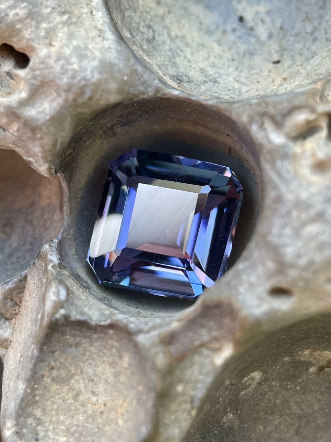Close-up of a 3.51ct Tanzanite nestled in natural rock, displaying its mermaid, green, and purple color blend.