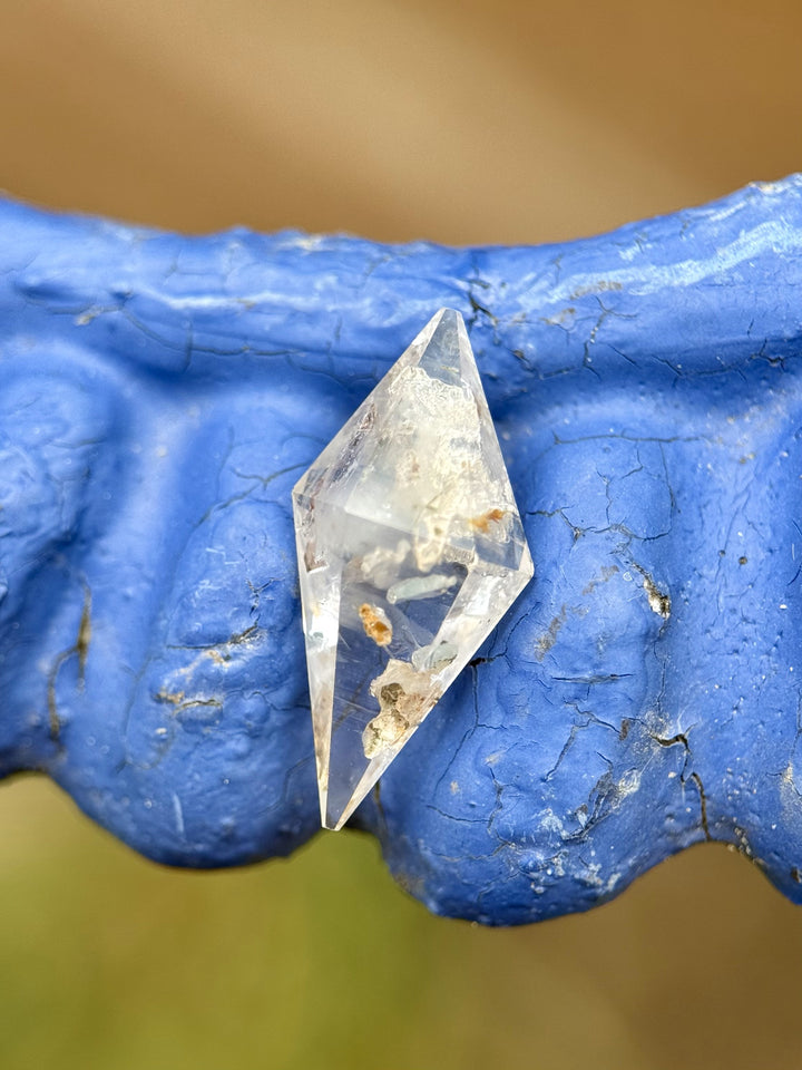 Natural 2.85-carat sapphire with earthy silvery gray hues and a geometric rhombohedral shape displayed on blue background.