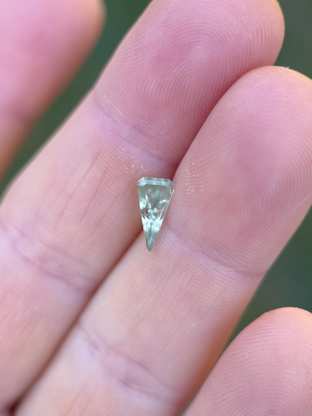 1.57ct yellow-green sapphire from Malawi in a kite step cut, shown resting delicately on fingertips to showcase size and precision faceting.