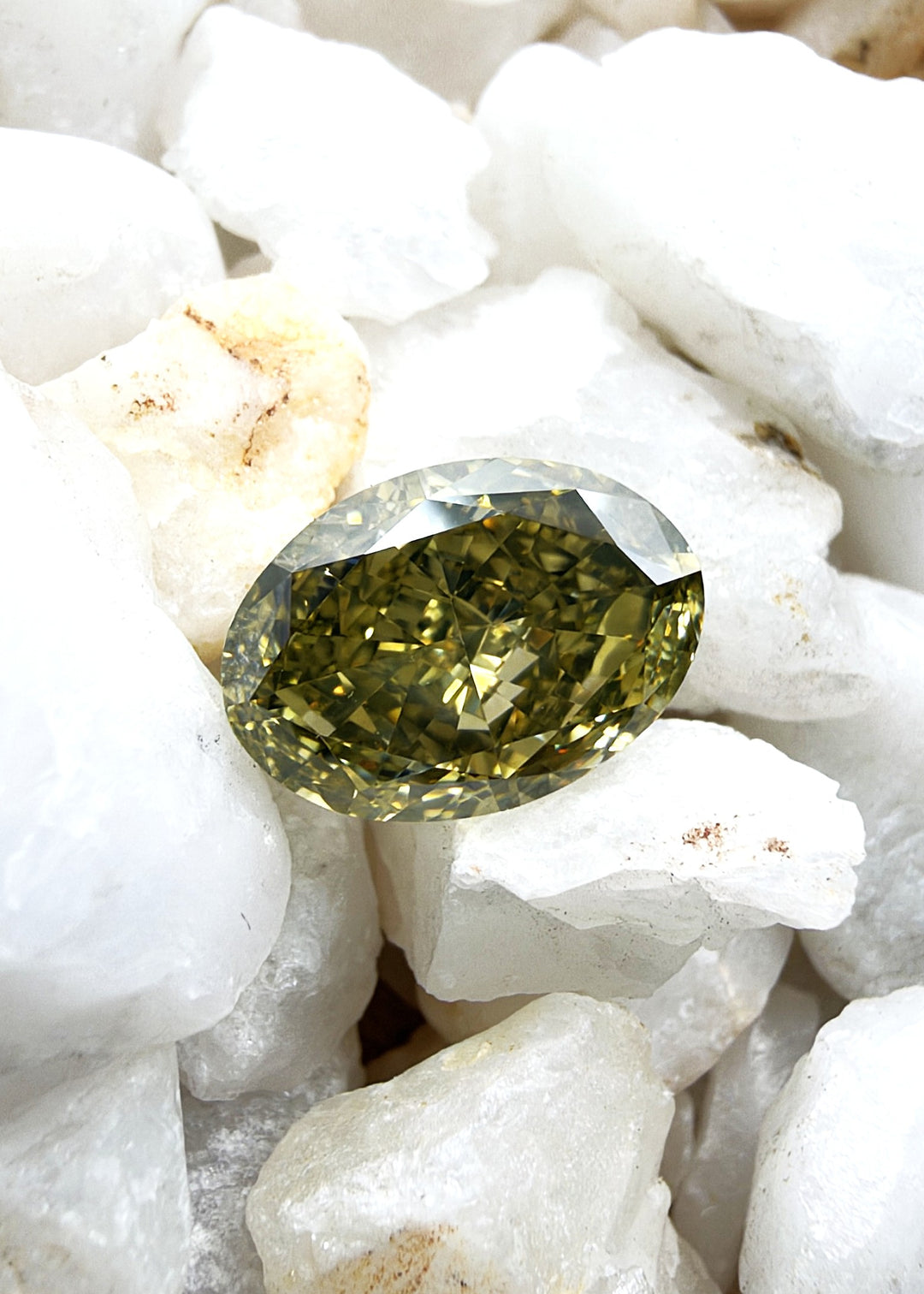 Oval cut Fancy Brownish Greenish Yellow diamond with a predominantly yellow color modified by greenish and brownish tones.