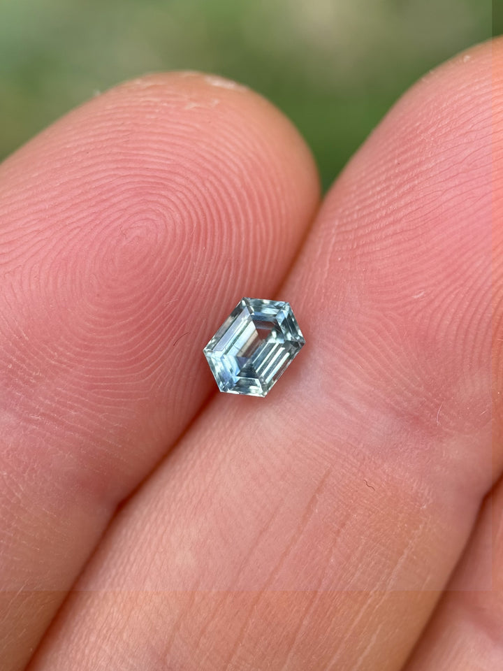 Montana parti sapphire resting on fingertip with geometric hexagonal step cut and vibrant untreated hues