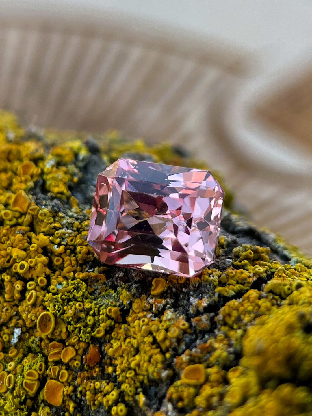 A close-up of a 1.45-carat peach champagne garnet with a modified octagonal step cut, placed on a textured mossy surface, originating from Madagascar.