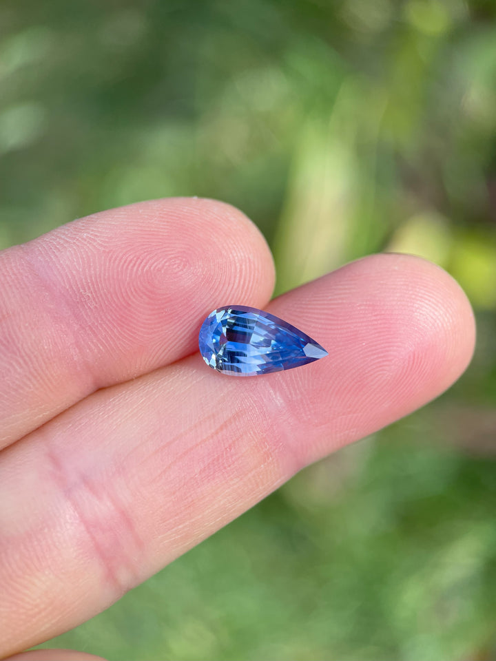 A close-up of a 3.14-carat pear-shaped parti sapphire, featuring a beautiful interplay of blue and yellow colors. Ethically sourced from Sri Lanka, this gemstone is untreated.