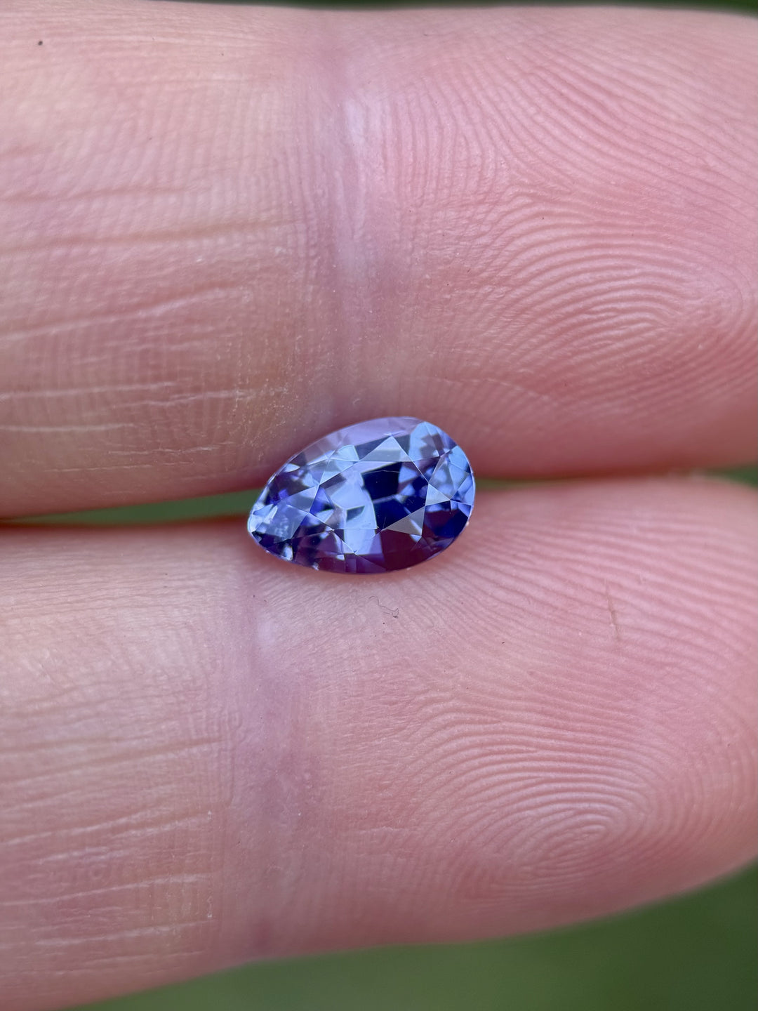 Natural 1.40ct Tanzanite resting on fingertip, showcasing precision poval cut with vivid purple and periwinkle color play