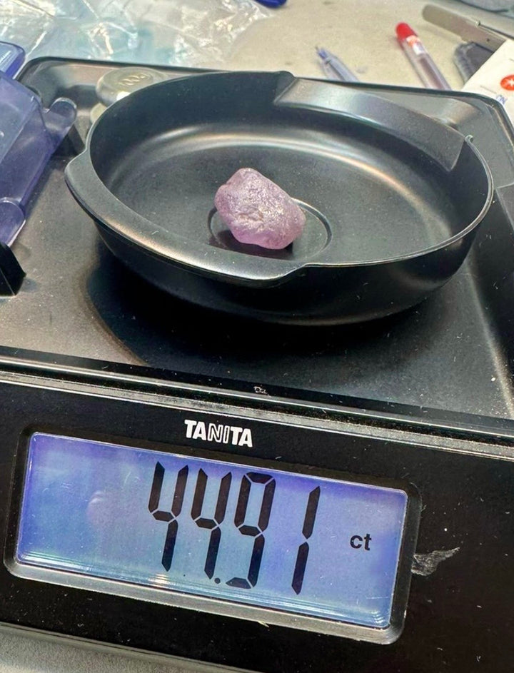 Large rough sapphire crystal on scale showing 44.91 carat preform before cutting.