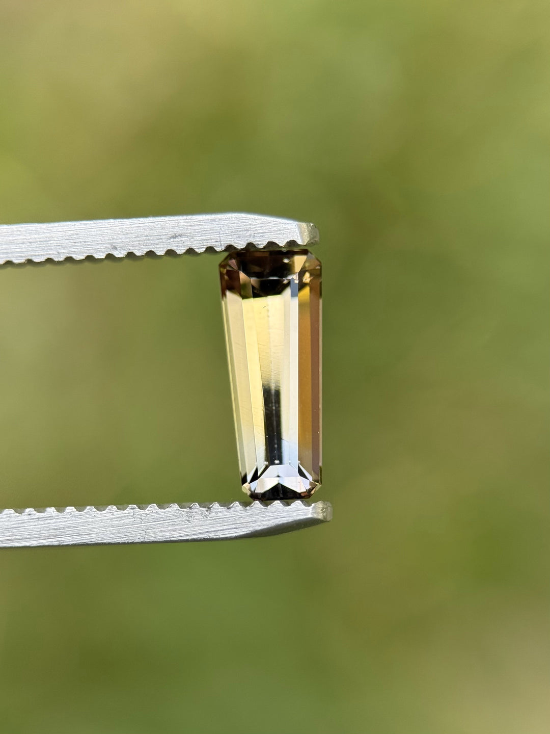 Close-up of 1.26CT multi-color Tanzanite in custom elongated tapered emerald cut.