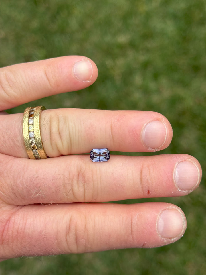 1.59-carat Tanzanite gemstone in radiant octagon cut with mermaid color blend of green, purple, and blue, displayed on fingers in natural light