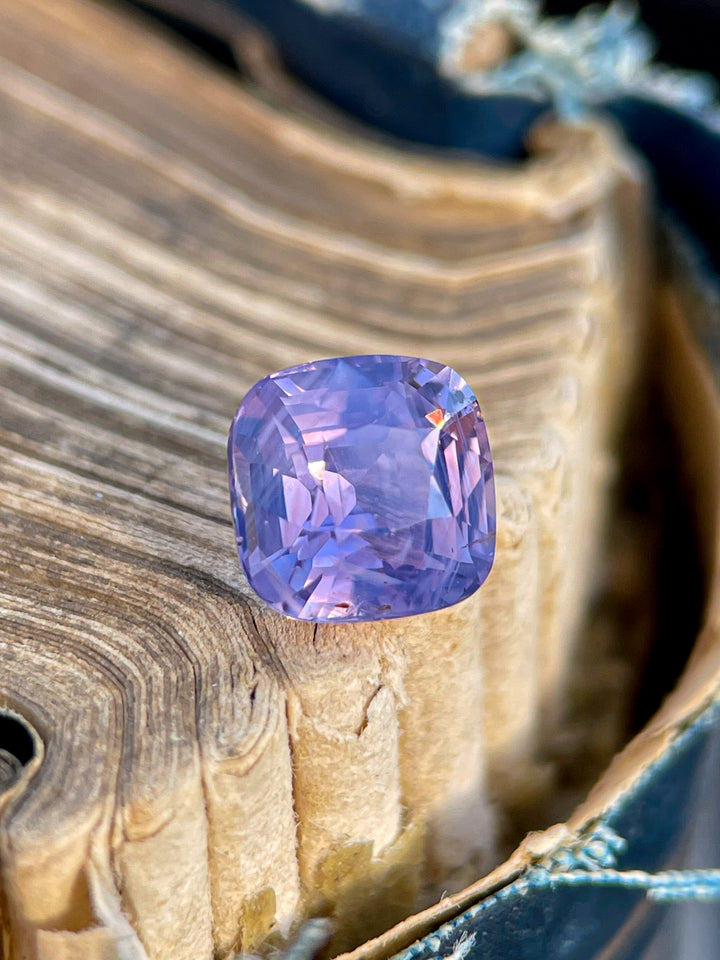1.53 carat cushion cut sapphire gemstone with opalescent pink and purple hues, untreated and sourced from Sri Lanka.