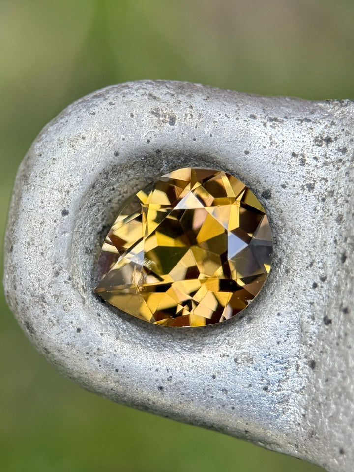 Close-up of 2.17CT tanzanite resting in metal groove, displaying warm fancy yellow and peach tones with intricate brilliance