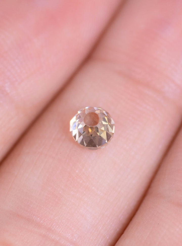 0.70-carat Mughal cut fancy light brown rosy champagne diamond placed on a fingertip for size reference, showing strong light return, faceting detail, and natural VVS1 clarity. Natural untreated diamond from South Africa.