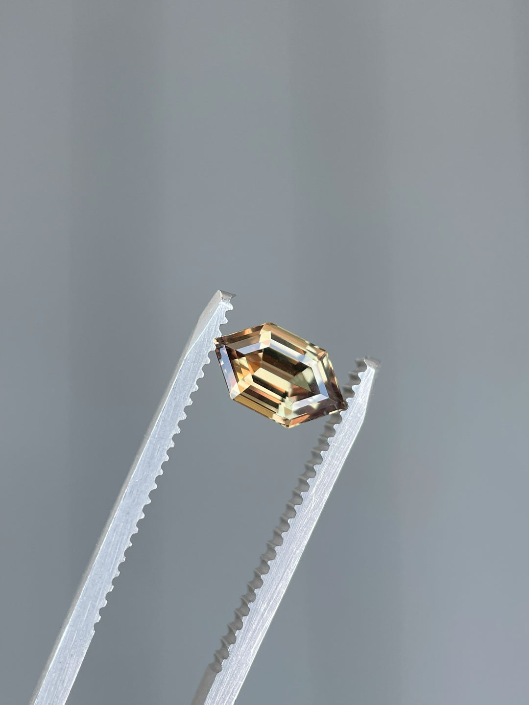 A beautifully faceted 1.22-carat sapphire from Songea, Tanzania, featuring a unique hexagon step cut and natural earthy tones of brown, orange, and pink.