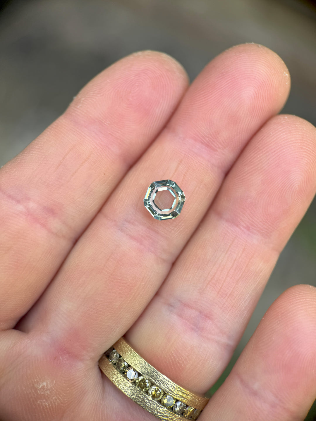 Light teal 2.09 carat sapphire held in tweezers, custom hexagon cut from Montana, untreated.