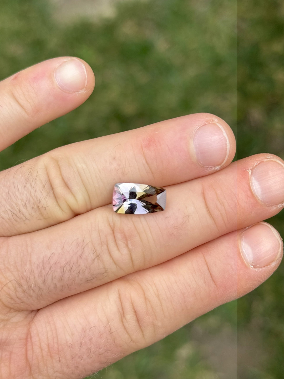 Elongated cushion cut Tanzanite gemstone on hand, 4.35 carats, unheated from Merelani Hills Tanzania, with striking multicolor zoning
