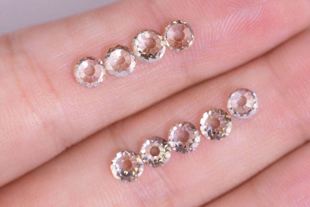 Nine Mughal cut fancy light brown VVS diamonds displayed on fingertips for scale, showing antique round faceting, open culets, and uniform sizing from South Africa