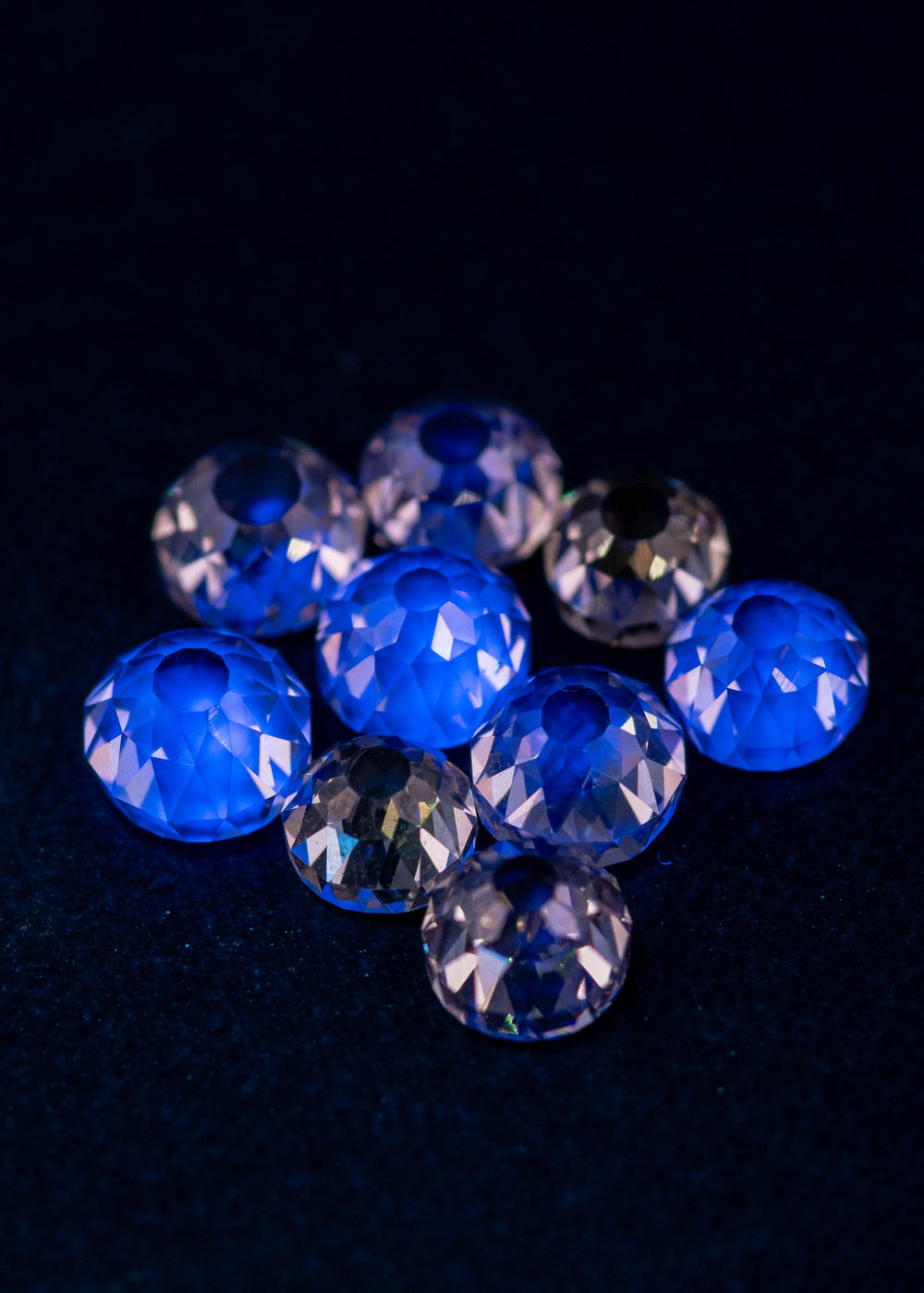 Mughal cut fancy light brown diamonds glowing under UV light, displaying light blue fluorescence across a 5.11 carat South African diamond parcel with antique faceting