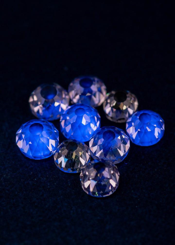 Mughal cut fancy light brown diamonds glowing under UV light, displaying light blue fluorescence across a 5.11 carat South African diamond parcel with antique faceting