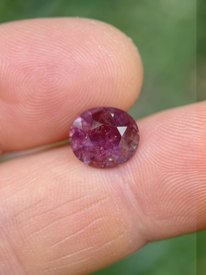 3.60 carat purplish red sapphire from Umba River Tanzania held between fingers, showing natural inclusions and vibrant color