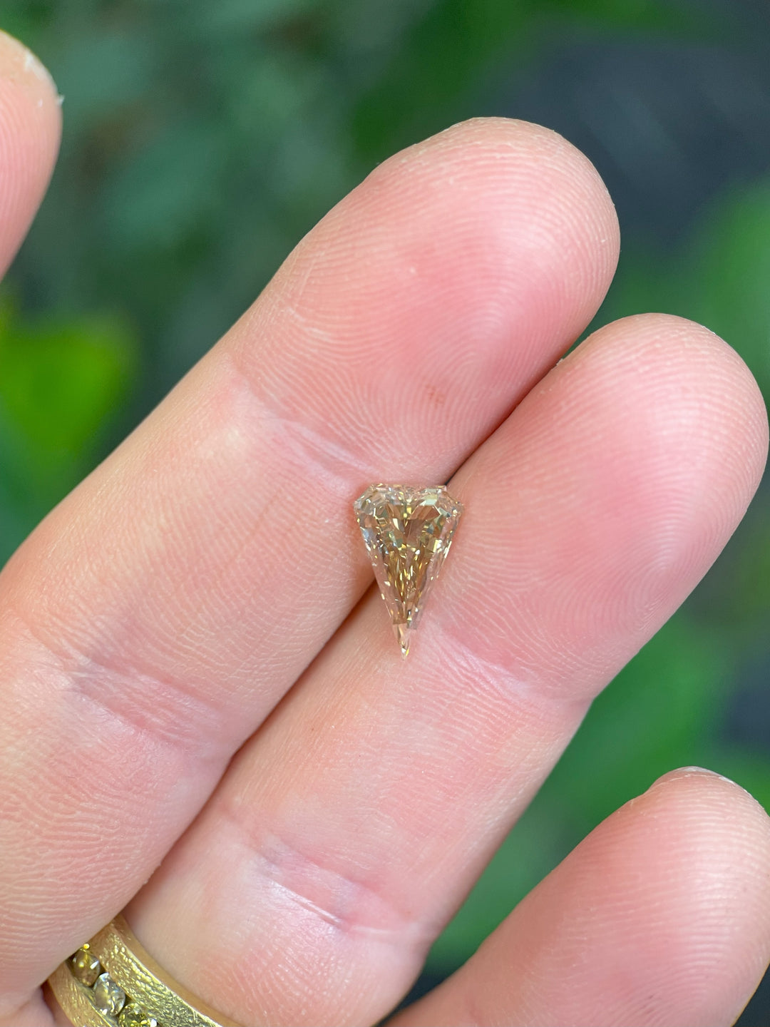 Handheld view of a 2.10-carat elongated kite cut diamond, revealing its exquisite champagne tones and precision-cut geometry.
