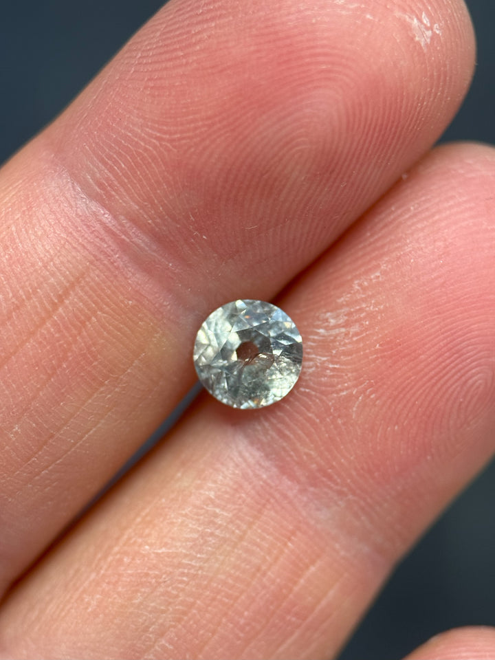 Sapphire held between two fingers against a neutral background