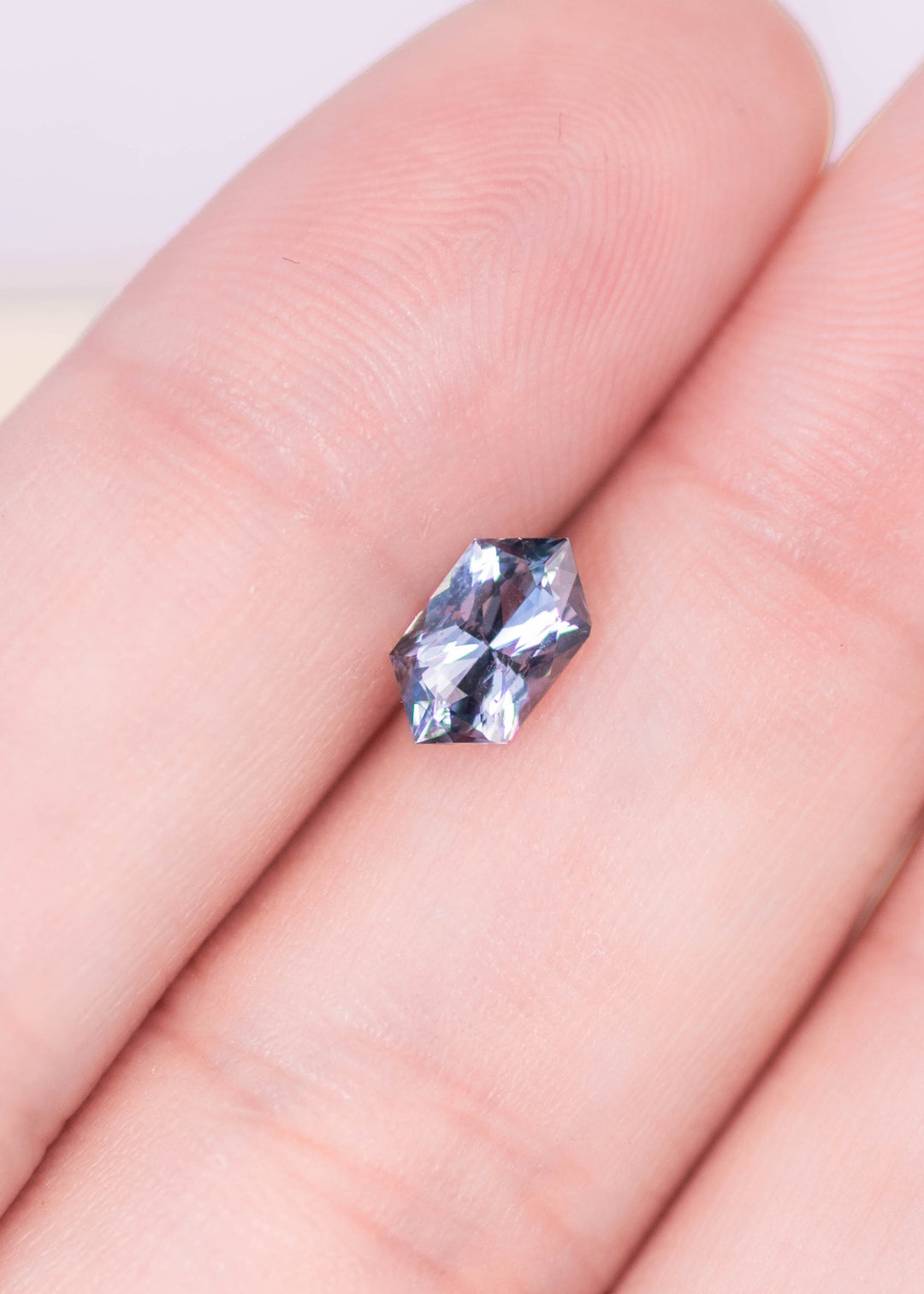 1.11 carat seafoam grey blue sapphire resting on fingertips, elongated hexagon mixed cut showing crisp facet symmetry and soft pastel blue-gray tones, natural unheated sapphire from Sakaraha Madagascar
