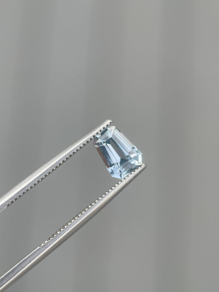 1.64 carat pale blue sapphire held by tweezers, revealing the intricate fancy mixed cut and clear, icy-blue hue. This gem, originating from Sri Lanka, highlights exceptional craftsmanship and natural beauty.