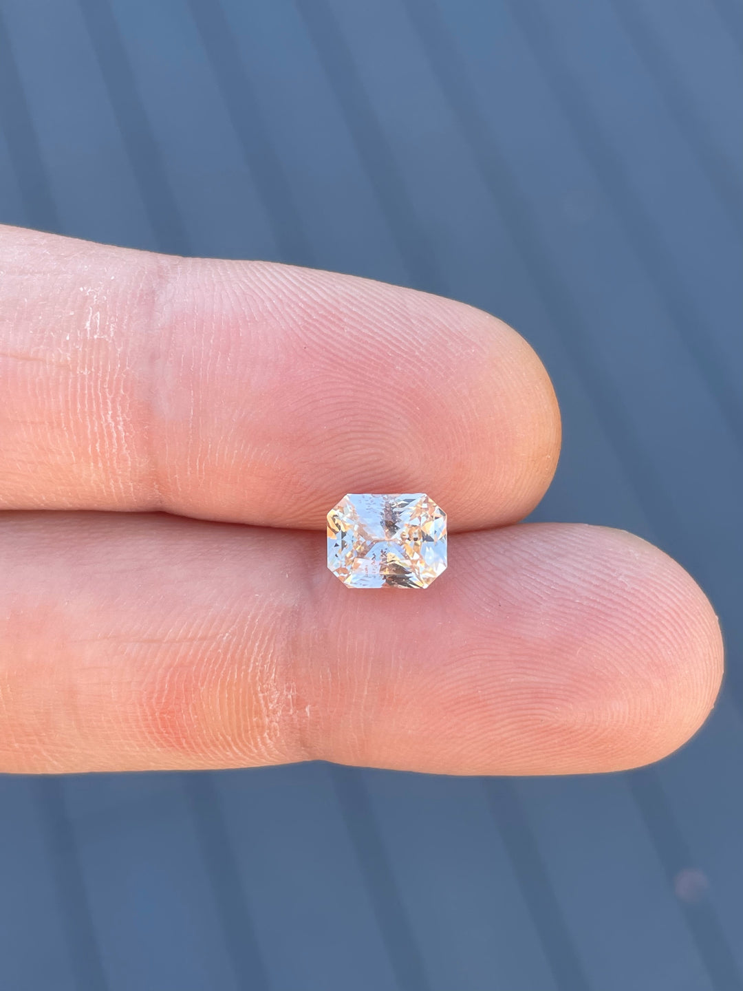 A close-up of a 2.55-carat peach champagne sapphire with an octagonal mixed cut. The untreated gemstone features warm peach and champagne tones, adding elegance to its natural beauty.